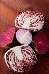 Purple vegetables on a brown wooden table. Red beetroot, red onion and radicchio salad on a wooden background. Healthy purple vegetables for cooking