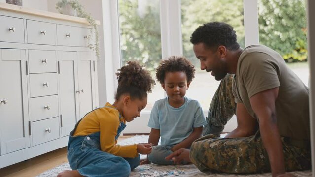 Army Father In Uniform Home On Leave With Children Doing Jigsaw Puzzle Together