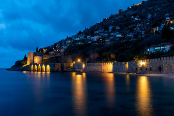 Naklejka premium Alanya, Turkey. April 8th 2021.Beautiful view of Alanya peninsular and the old Shipyard and castle walls from the harbour at night