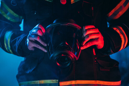 Firefighter holding a mask in front of him in an uniform