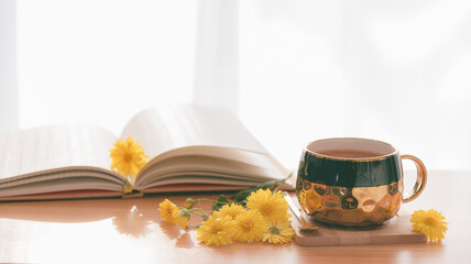 A cup of Chrysanthemum tea with hot steam on table and flowers, white curtain background,Healthy beverage,juice for drink,Help reduce blood pressure,prevent heart disease, Herbs and medical concept.