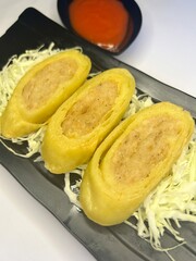 Chicken Egg Rolls, Japanese homemade chicken egg rolls served on a black plate with chopped cabbage and chili sauce