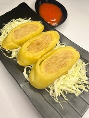 Chicken Egg Rolls, Japanese homemade chicken egg rolls served on a black plate with chopped cabbage and chili sauce