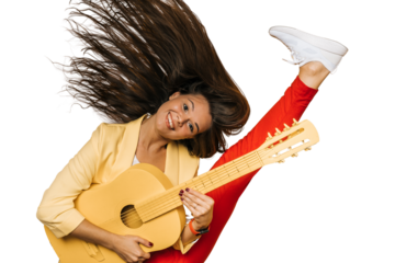 Young attractive brunette girl dressed in yellow jacket and red pants holding yellow guitar dancing with fluttering long hair and raising her leg high on transparent background. Happy people concept.