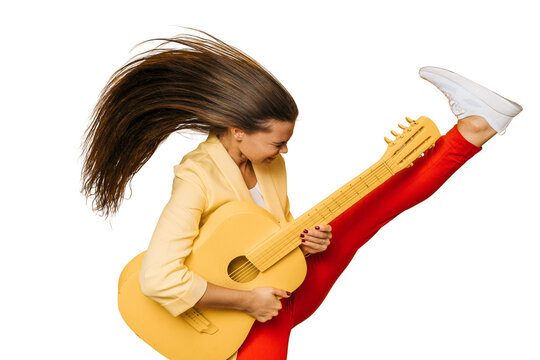Young excited Italian girl dressed in yellow jacket and red pants holding yellow guitar dancing with fluttering long hair and raising her leg high on transparent background. Happy people concept.