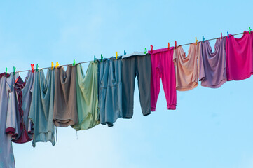 Multi-colored clothes after washing hang on a rope in the open to dry.
