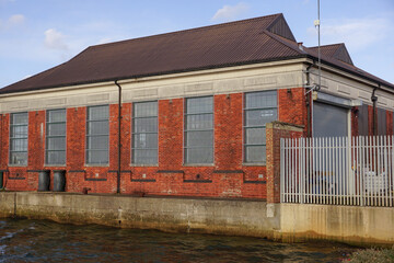 old warehouse building beside river canal. Industrial factory building exterior in city