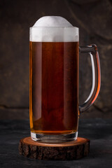 a glass of cold dark beer in a mug on a dark background