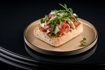 delicious crispy bruschetta with chopped pieces of jamon and arugula leaves