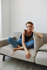 Fototapeta premium Young woman with short haircut hair having fun at home on the couch smile and happiness, vacation at home, natural posing without filters, free copy space