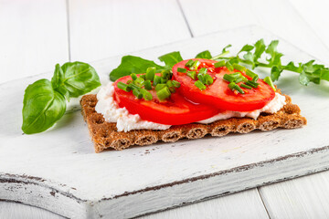 Crispbread with curd cheese, tomatoes, green onions, arugula and basilica. Delicious and healthy breakfast. Copy space