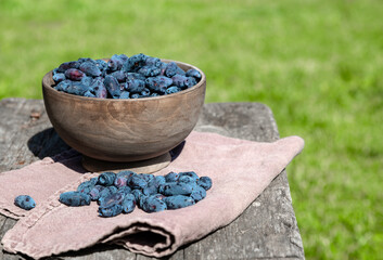 Honeysuckle in a wooden bowl on an old wooden table on a sunny day