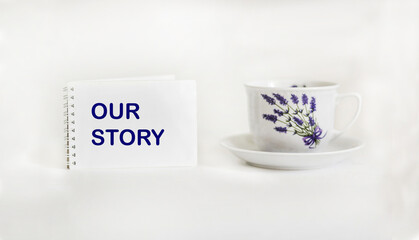 Our story, text on notepad and white background with beautiful tea mug, motivational concept for life and business
