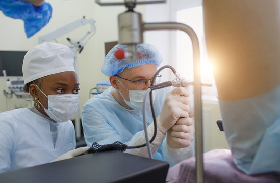 a proctologist with an assistant performs an operation on a patient lying on a proctological chair.