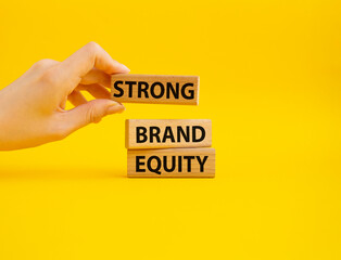 Strong Brand Equity symbol. Concept words Strong Brand Equity on wooden blocks. Businessman hand. Beautiful yellow background. Business and Strong Brand Equity concept. Copy space