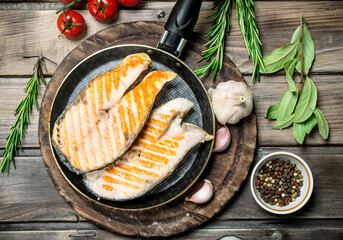 Grilled salmon in a pan with spices and herbs.