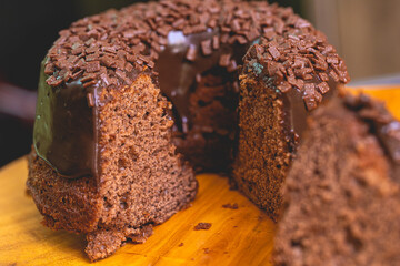 Um bolo de chocolate com calda de chocolate e decorado com chocolate granulado sobre uma tábua de...