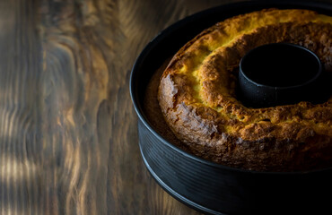Homemade cake with cocoa in a mold on a rustic wooden background.