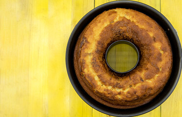 Homemade cake with cocoa in a mold on a rustic wooden background.
