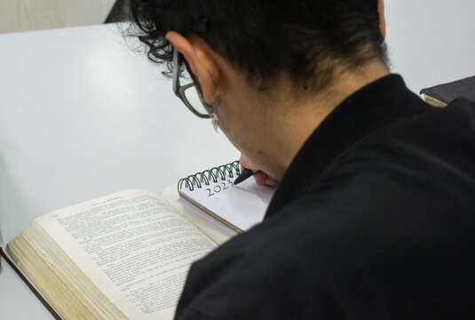 Joven escribiendo en un cuaderno sus metas para el 2023