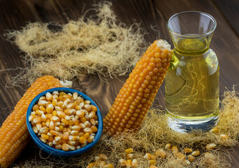 Close-up of dry corn cob, cornmeal, corn oil on rustic wooden table.
