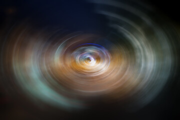 Defocused abstract dark background with bright light streaks and trails with spin blur effect. High resolution full frame abstract blurred background with copy space.