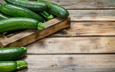 Green zucchini in wooden tray.