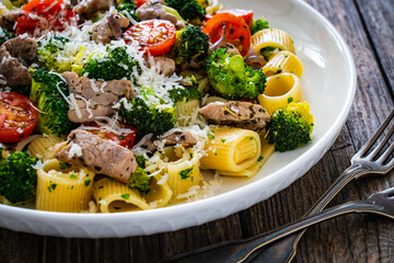 Pasta with roasted pork loin, broccoli, parmesan and cherry tomatoes on wooden table