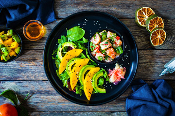 Salmon ceviche with lemon, mango and avocado on wooden table
