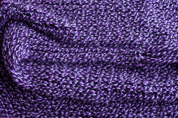 Knitted warm purple sweater or scarf handmade. Cozy composition in the home atmosphere. Wool fabric texture close up background. Comfortable style cloth. Wavy folds material.