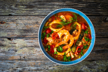 Seafood and fish soup on wooden table

