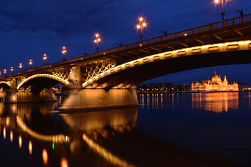 the Margaret bridge in Budapest at blue hour. perspective view. brightly illuminated steel arches. the Parliament at a distance. reflection on the water. tourism and travel concept. transportation.
