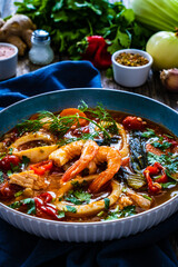 Seafood and fish soup on wooden table
