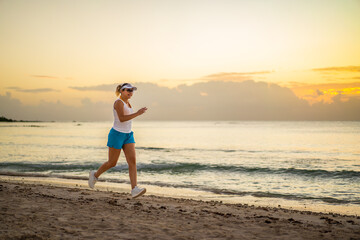 Woman running on sunny, tropical beach at daybreak
