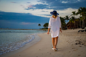 Woman walking on sunny, tropical beach at daybreak
