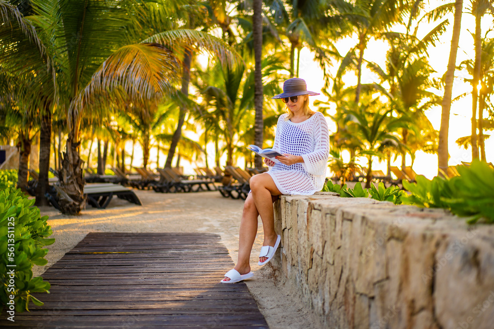 Wall mural woman relaxing on beach reading book