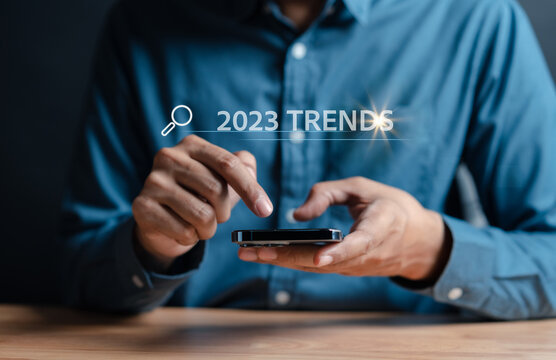 New business target start up in new years, Businessman using smartphone to input keyword of 2023 trends inside infographic searching engine bar for marketing, business planning change concept.