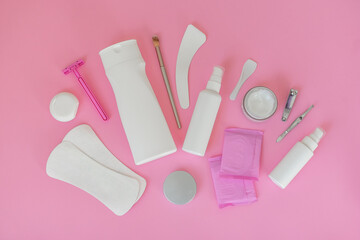 Women's personal care products on a pink background. Pads, razor, cream, spray, tweezers.