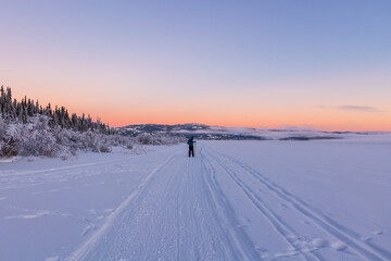 Fototapeta na wymiar One person skiing on cross country ski trails during winter time at sunset. 