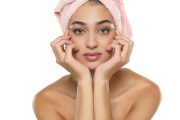 A pretty young woman with towel on her head posing on a white background