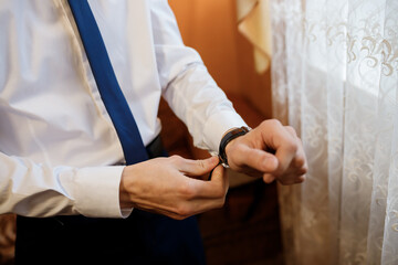 Obraz na płótnie Canvas Businessman checking time on his wrist watch, man putting clock on hand. Groom getting ready in the morning before wedding ceremony. Men Fashion