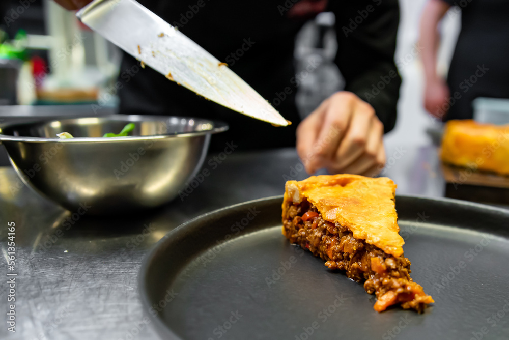 Wall mural chef hand preparing a gourmet meat pie on restaurant kitchen