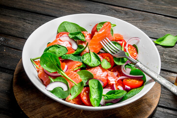 Fish salad. Salad with slices of salmon, tomatoes and spinach with lime juice.