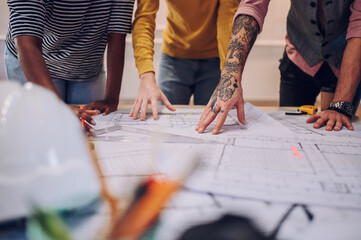 Multiracial team of architects having a meeting while using blueprints