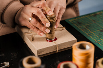 Craftsman puts a stamp on sealing wax on handmade gifts in the workshop. Process of sealing waxing...