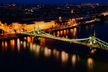 Fototapeta na wymiar the Liberty bridge in Budapest. aerial evening view or blue hour. brightly illuminated steel structure. reflection on water. tourism and travel concept. transportation and design. night photo