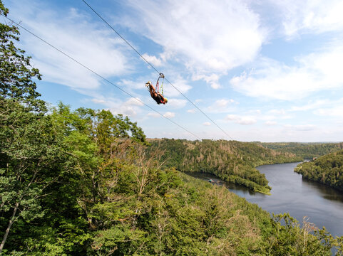 Person beim Ziplining vom Berg Richtung See ins Tal