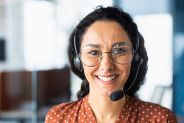 Close up portrait of latin american woman inside modern office with headset for video call, woman...