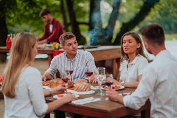 Group of happy friends having picnic french dinner party outdoor during summer holiday vacation near the river at beautiful nature