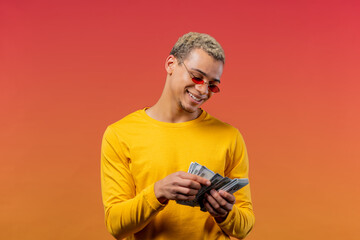 Satisfied man counting USD currency. Young millenial guy or student counts money - dollars banknotes on gradient wall. Symbol of success, gain, salary, benefit, investments.